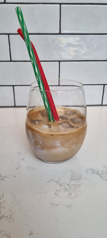 Glass of iced coffee with two straws against a tiled wall background